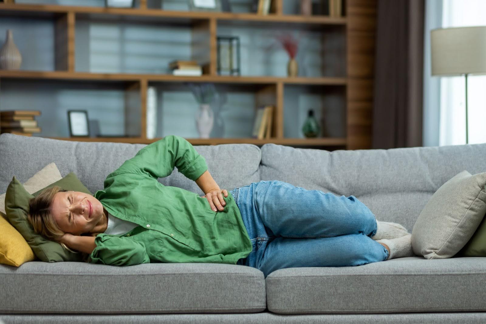 A woman in pain lying on the couch.