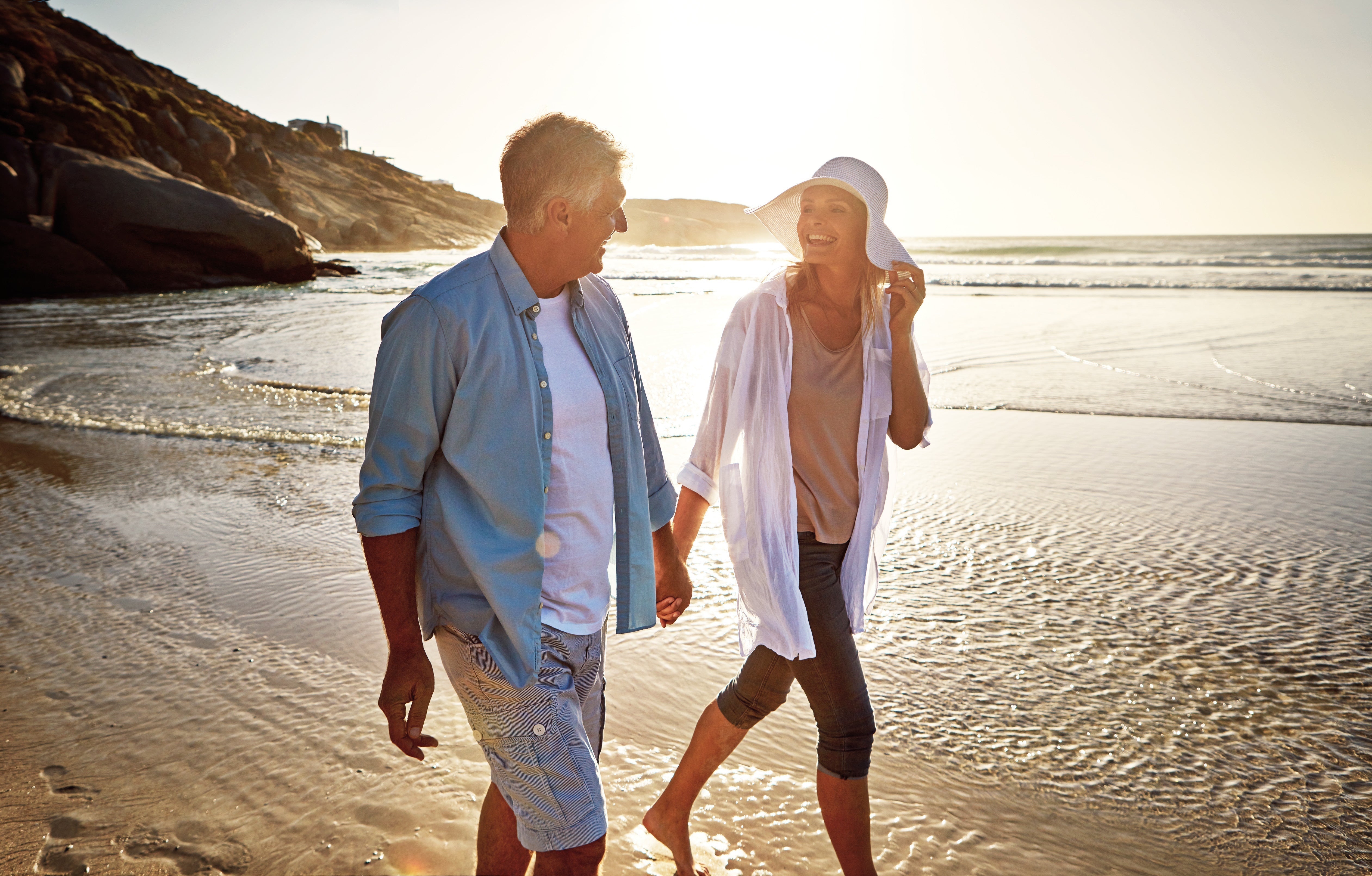 A man and a woman smiling on the beach.