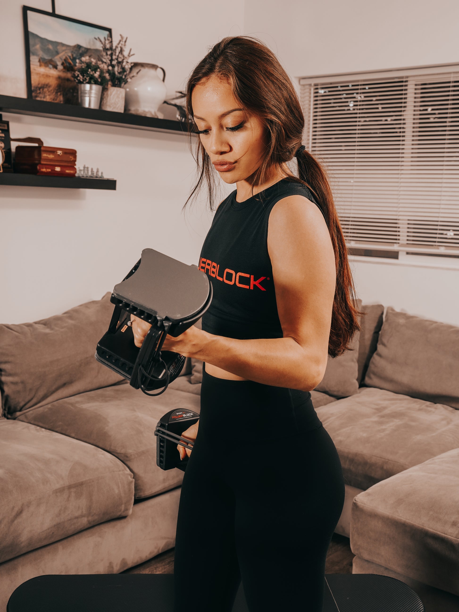 Woman doing a bicep curl with a Powerblock 24 adjustable dumbbell.